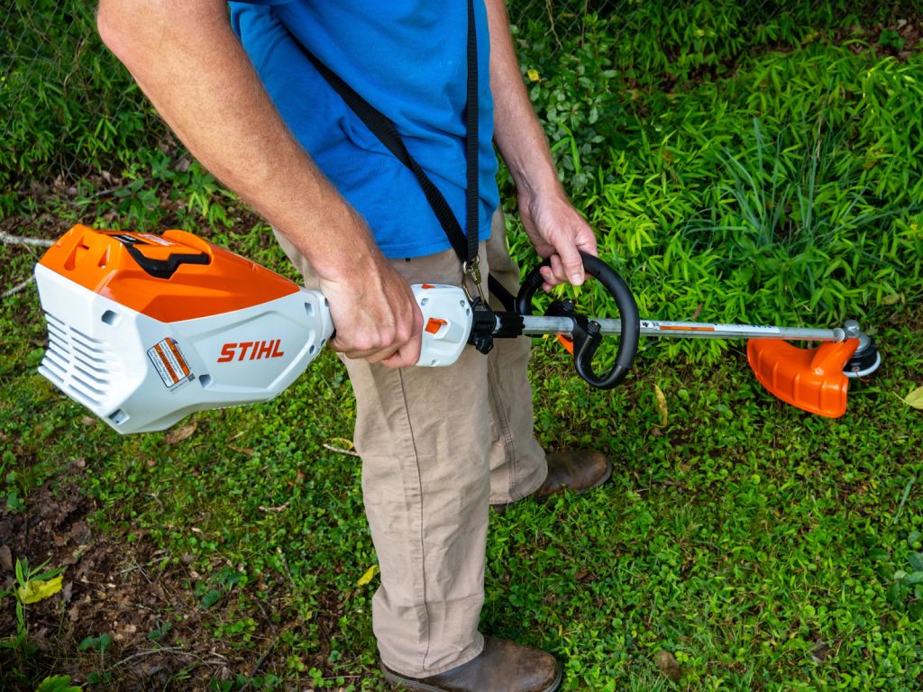 A man holding a battery powered trimmer.
