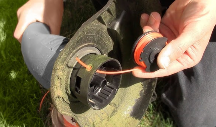 hands replacing string trimmer spool line during lawn tool maintenance