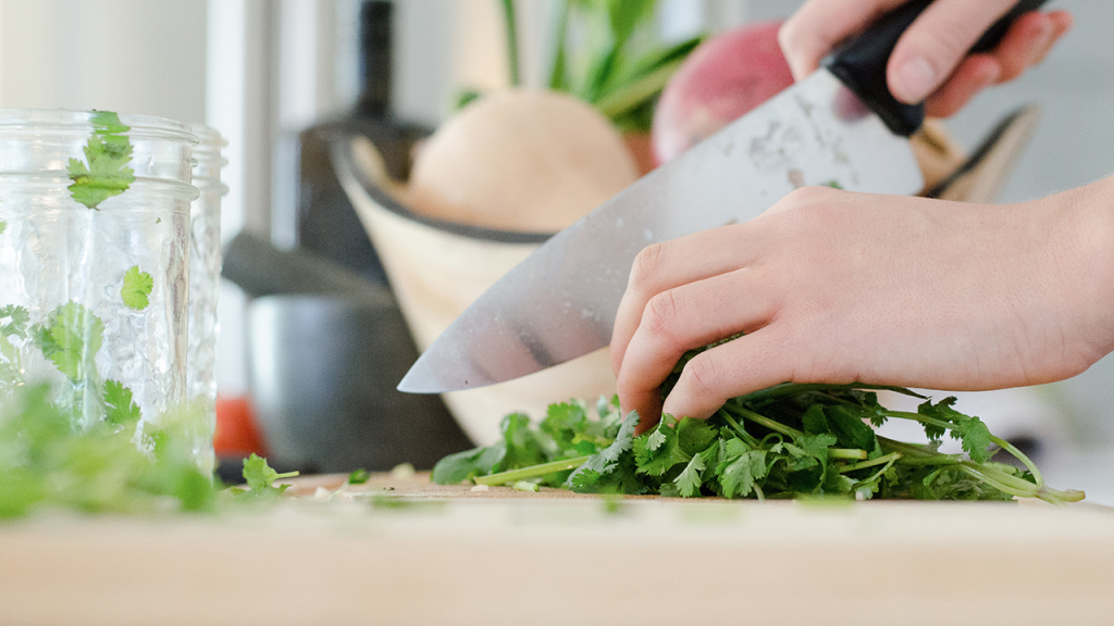 chopping fresh cilantro on a cutting board for homemade cooking and meal preparation