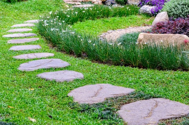 stone pathway through a well-maintained lawn and landscaped garden border