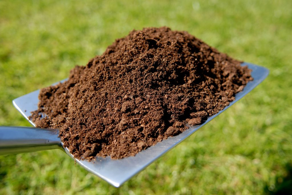 shovel loaded with organic compost for enriching soil and boosting lawn health