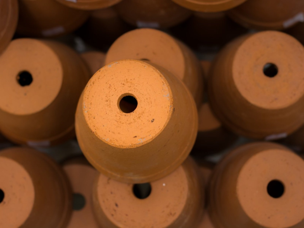 A pile of upside down terracotta pots showing their drainage hole.