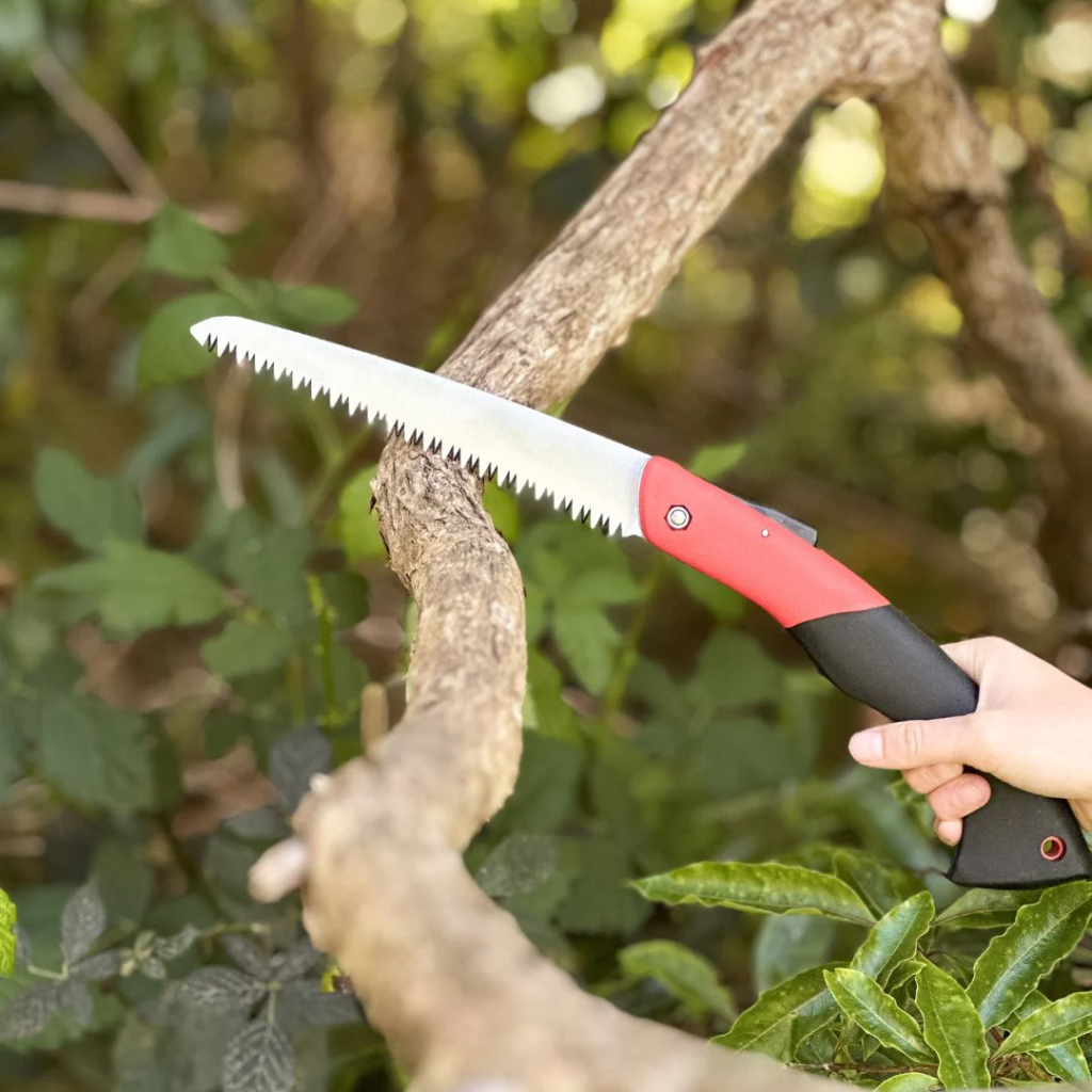 A pruning saw being used to cut a branch.