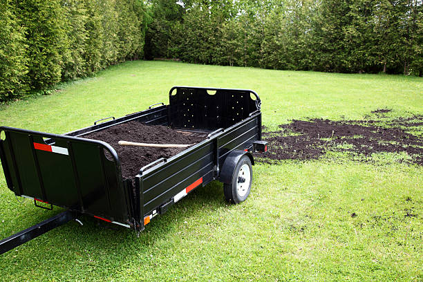 Soil being placed on patched of a lawn from a flat wagon.