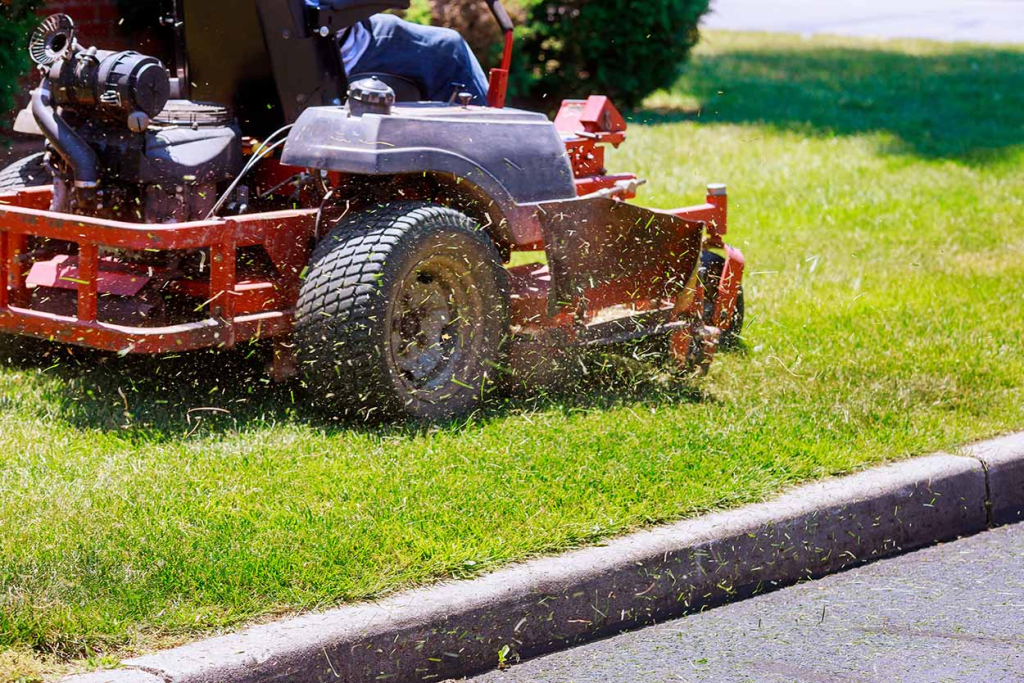 A gardener using a riding lawn mower to cut a patch of grass.
