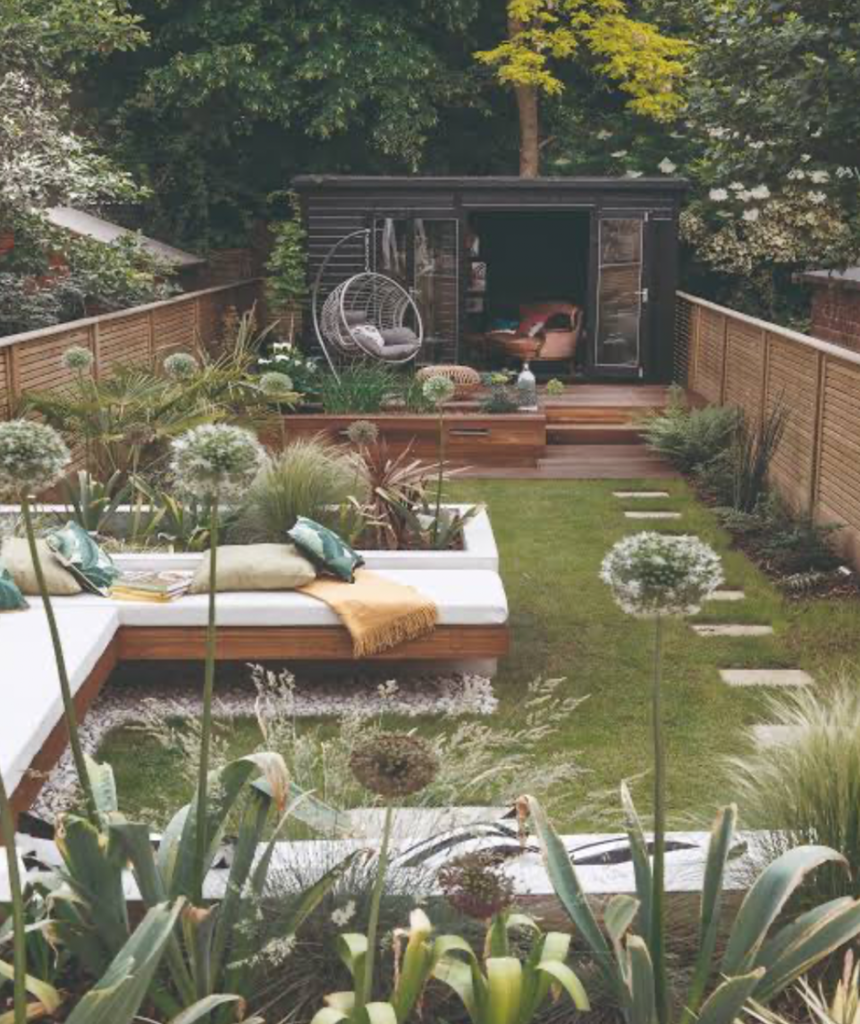 Long narrow garden with built-in seating, garden office, and layered planting