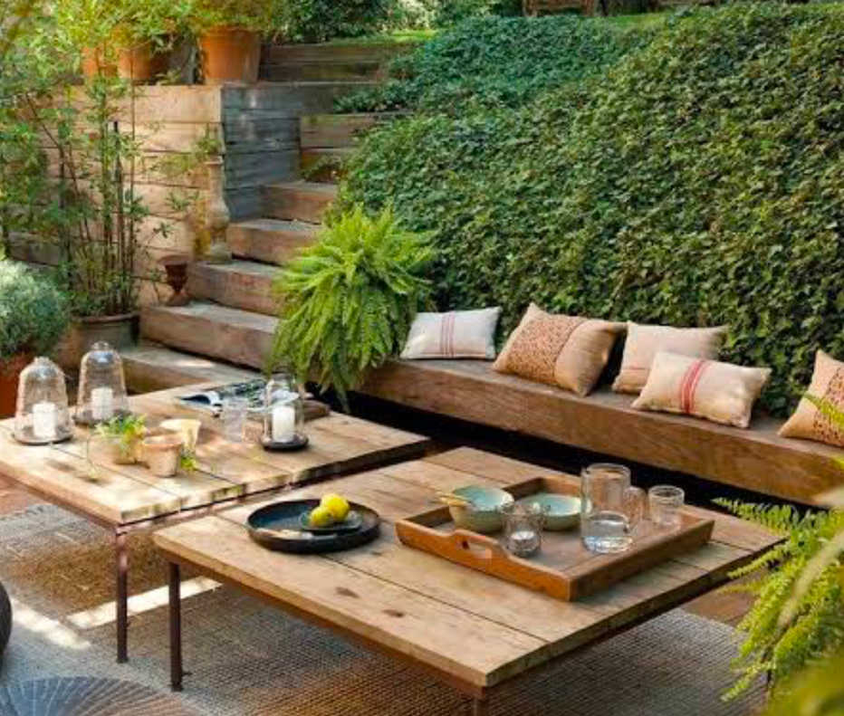 Cozy garden patio with built-in wooden seating, low tables, and lush ferns