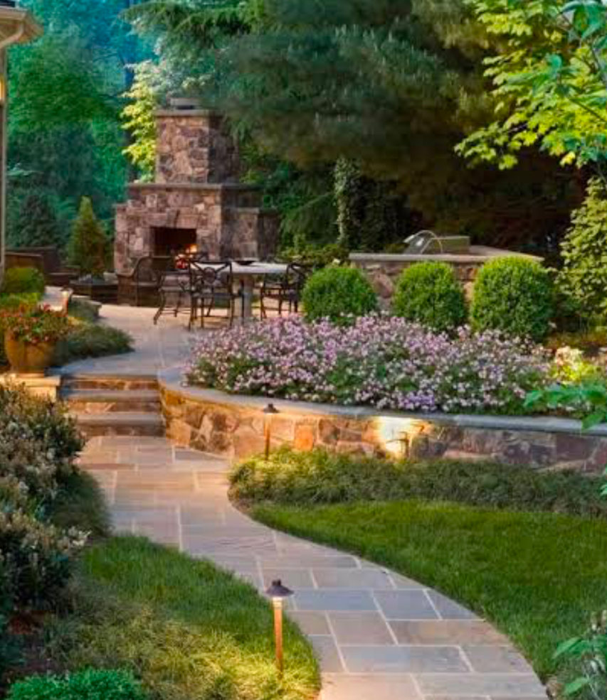Backyard stone walkway with fireplace and garden lighting