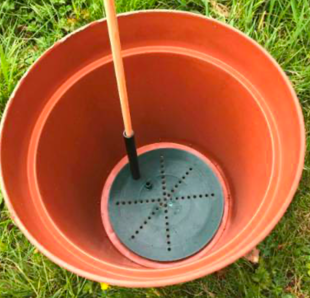 Self-watering planter setup showing reservoir base inside a large pot