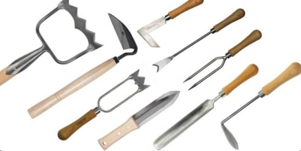 Traditional manual gardening tools including hoe, cultivator, and hand fork