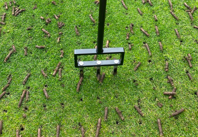 A foot powered plug aerator being used on a lawn.