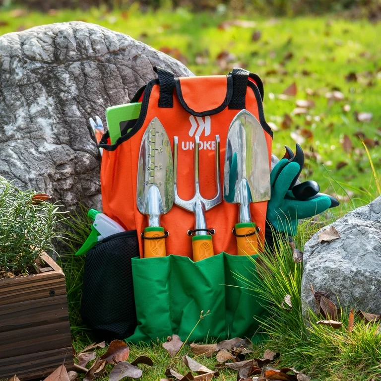 A pack next to a boulder in a field with gardening tools in the pockets.