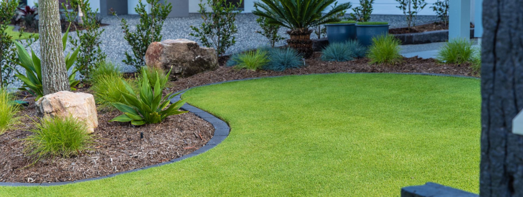 Modern landscaped yard with curved lawn edging, mulch beds, and ornamental plants