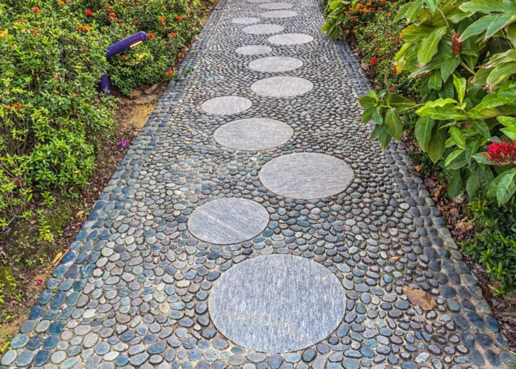 Garden path with circular stepping stones on pebbled surface.