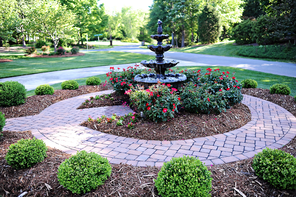A garden with a fountain in its center used as a front yard centerpiece. 