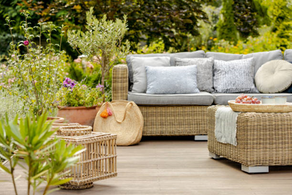 Rattan outdoor sofa set on garden deck with plants and wicker table