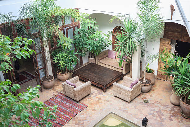 Traditional Moroccan house with an interior courtyard with plants, carpet, armchairs and swimming pool.