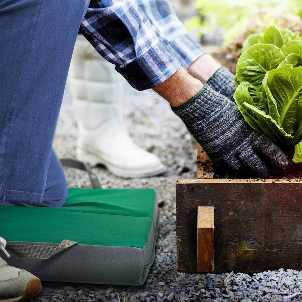 A gardener using a knee pad as they work in a plot.