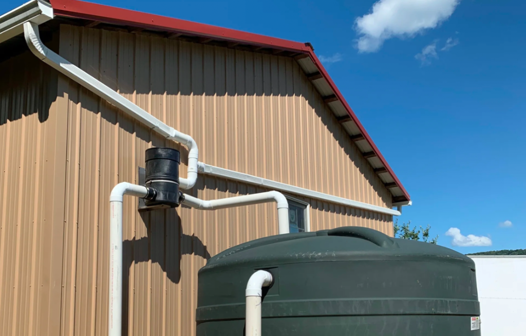 A large rain water collection storage tank attached to the gutters of a shed.