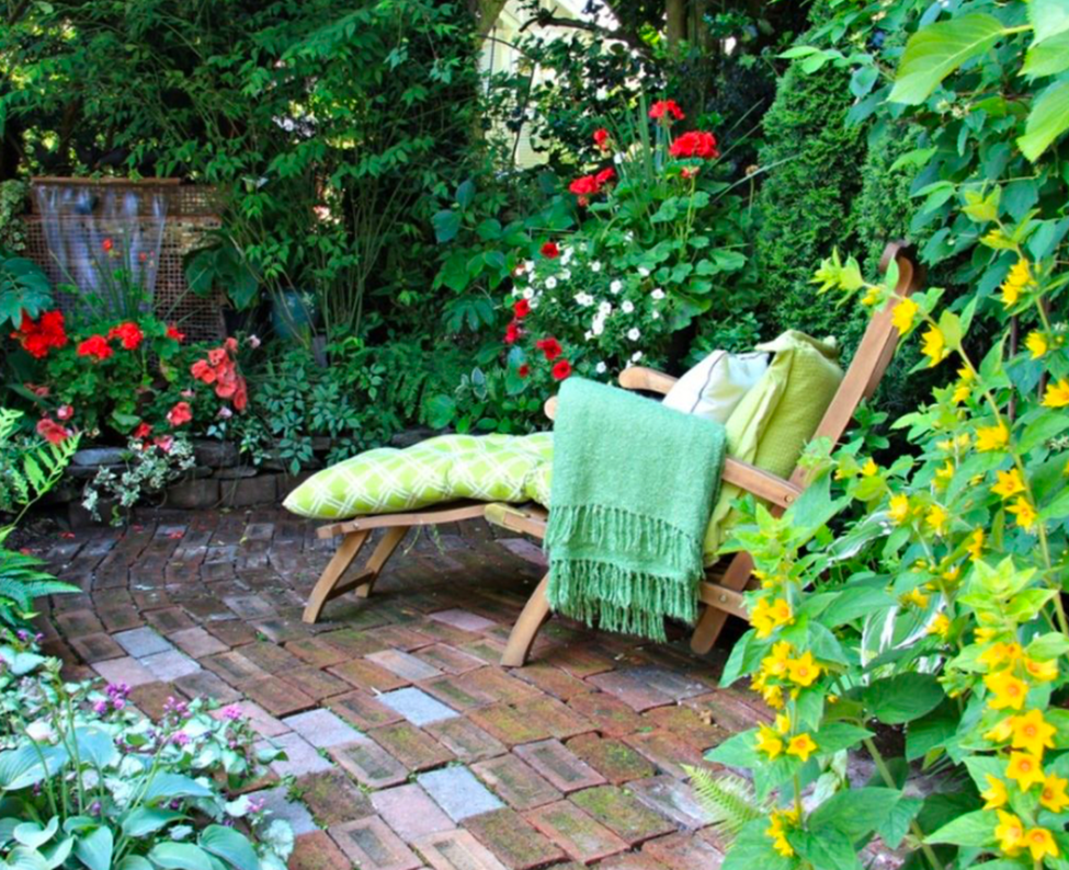 Cozy garden corner with lounge chair surrounded by colorful flowers and lush greenery