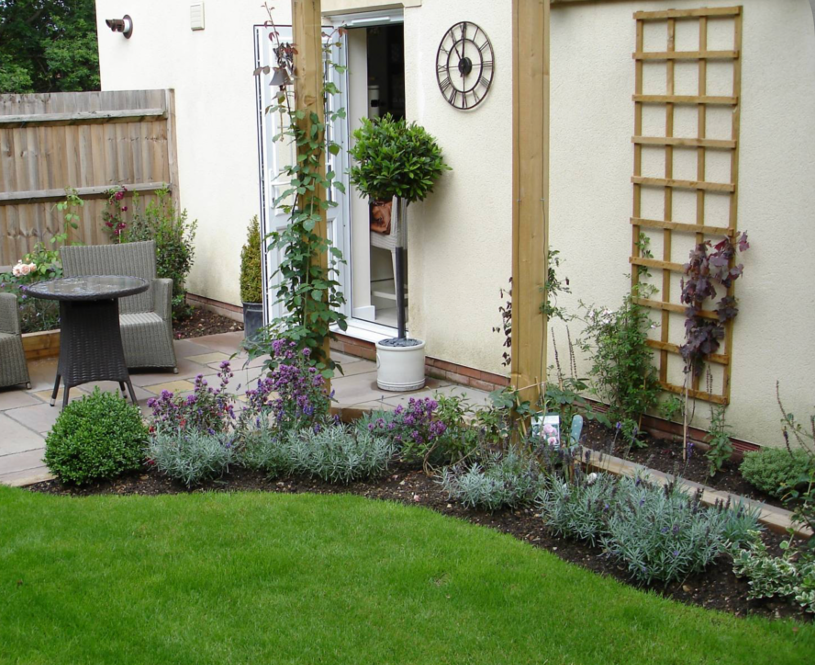 Small patio garden with trellis panels, flowering plants, and neatly edged lawn