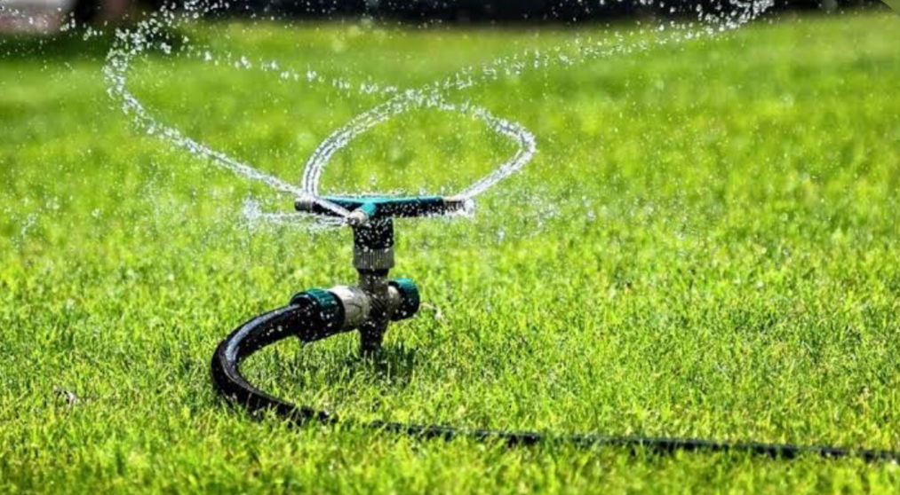 rotating sprinkler watering green lawn for healthy grass growth