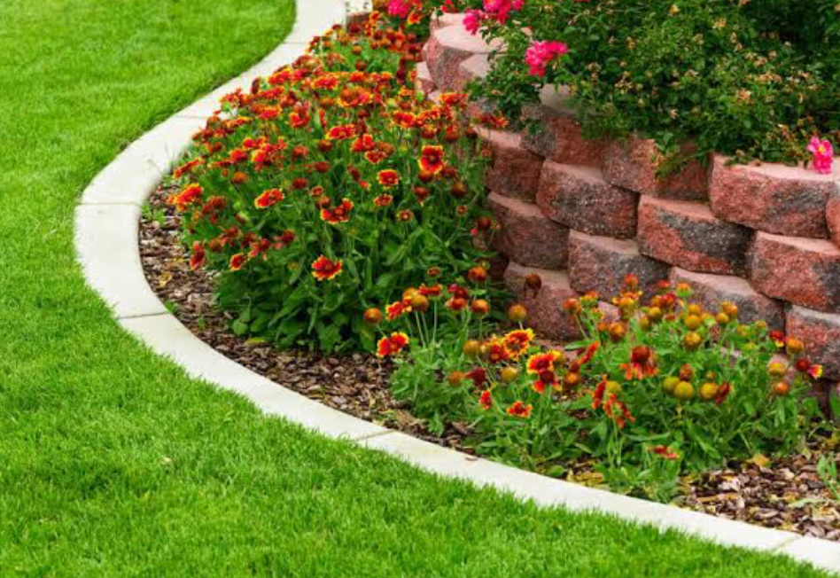 decorative stone garden edging with red flowers and landscaped lawn border